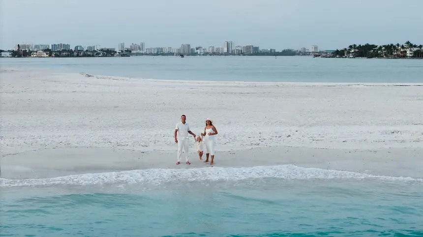 A family on the white sand at South Lido from above, the water on both sides and Sarasota across the bay