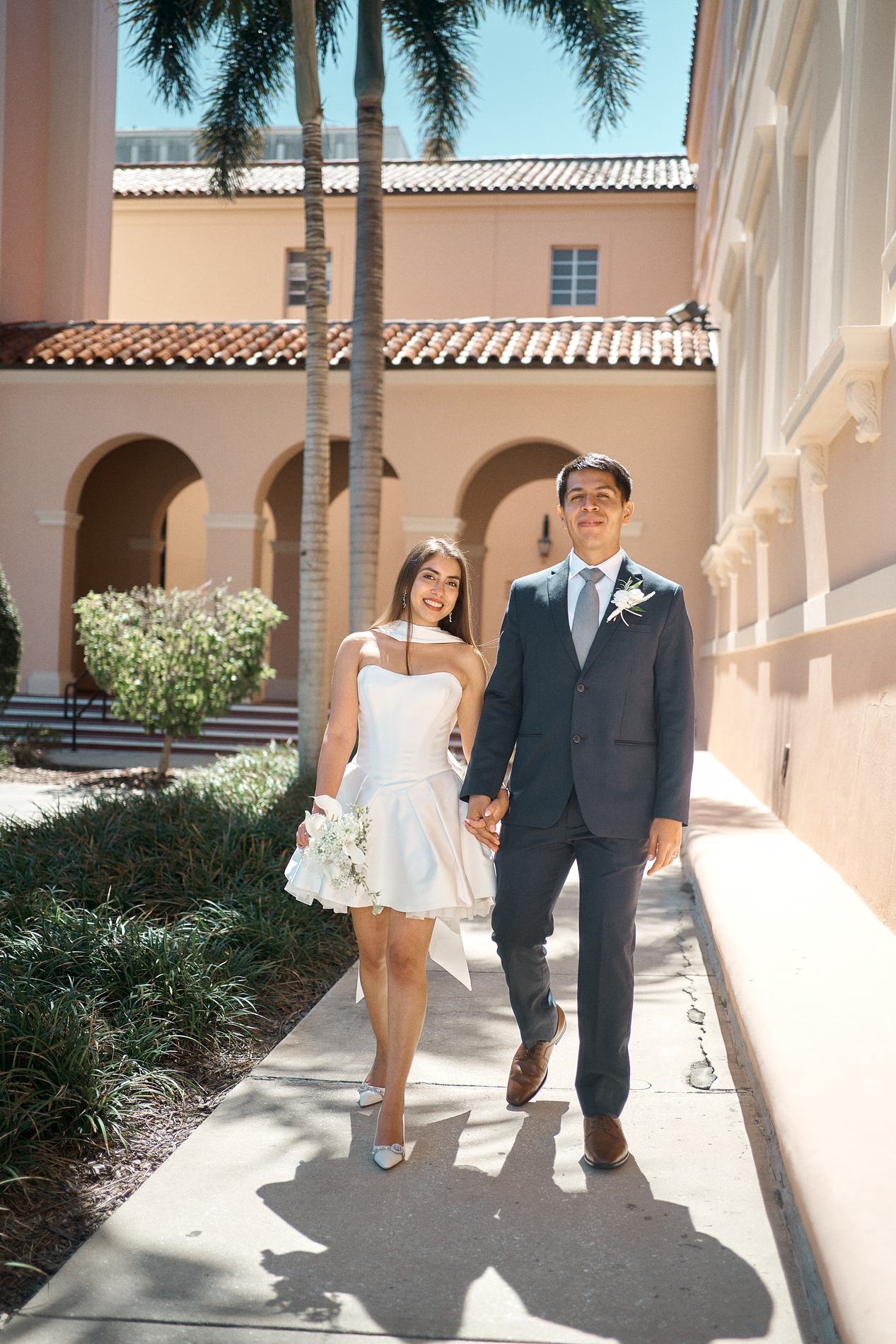 A newly married couple walking hand in hand through the arcade courtyard of the Sarasota Historic Courthouse