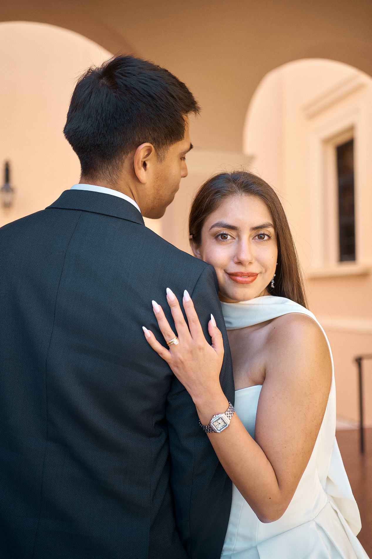 A bride resting her hand with the ring on the groom's shoulder under the arches of the Sarasota Historic Courthouse