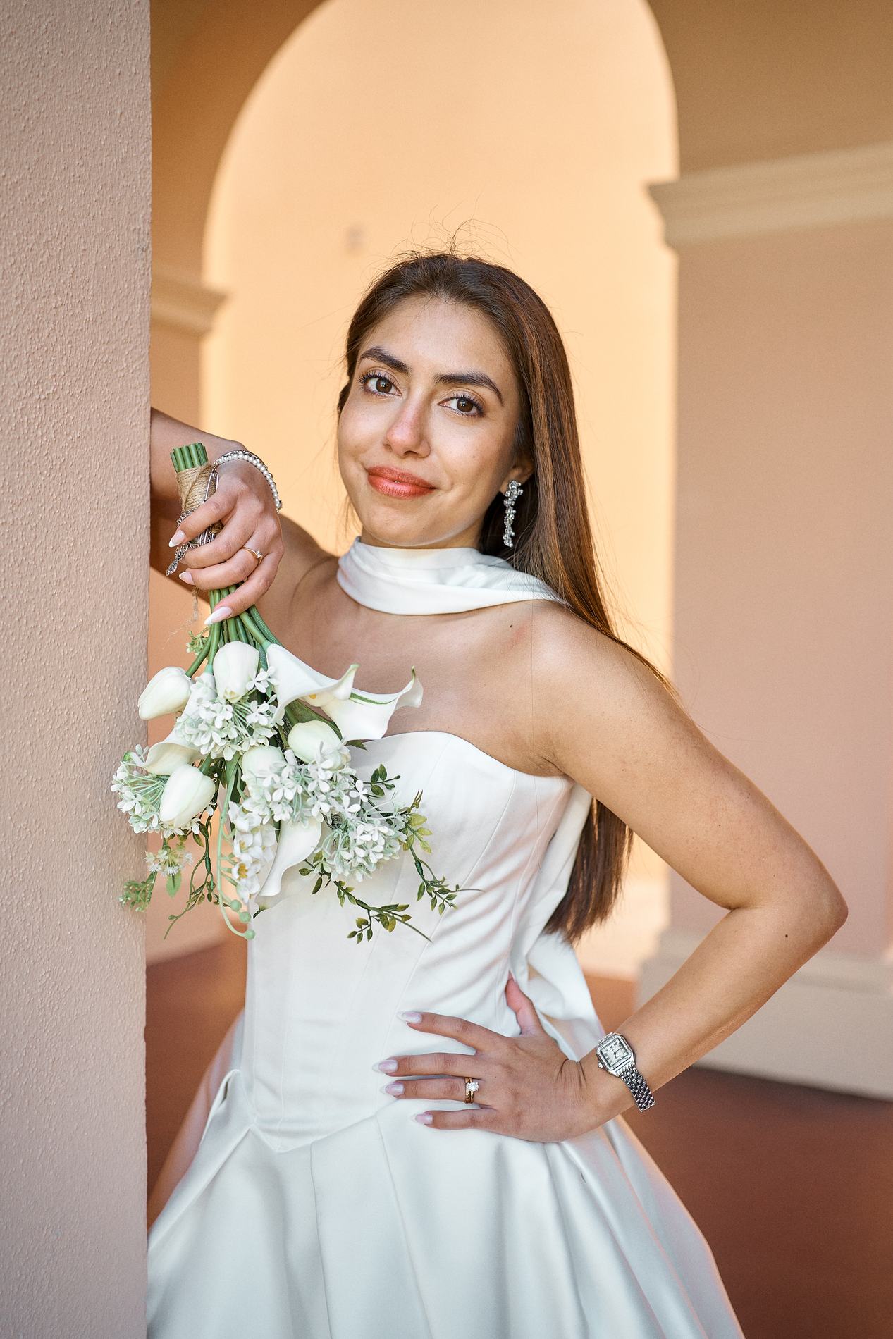 A bride with her bouquet leaning against an arch of the Sarasota Historic Courthouse