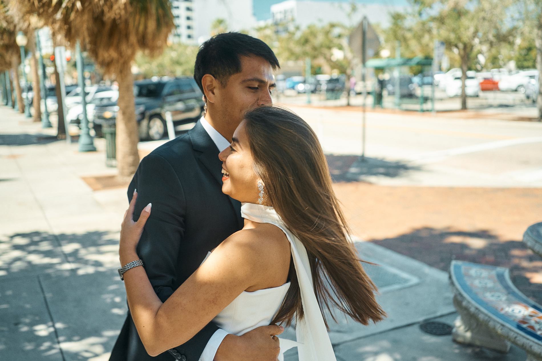 A bride and groom hugging on a sunny downtown Sarasota street