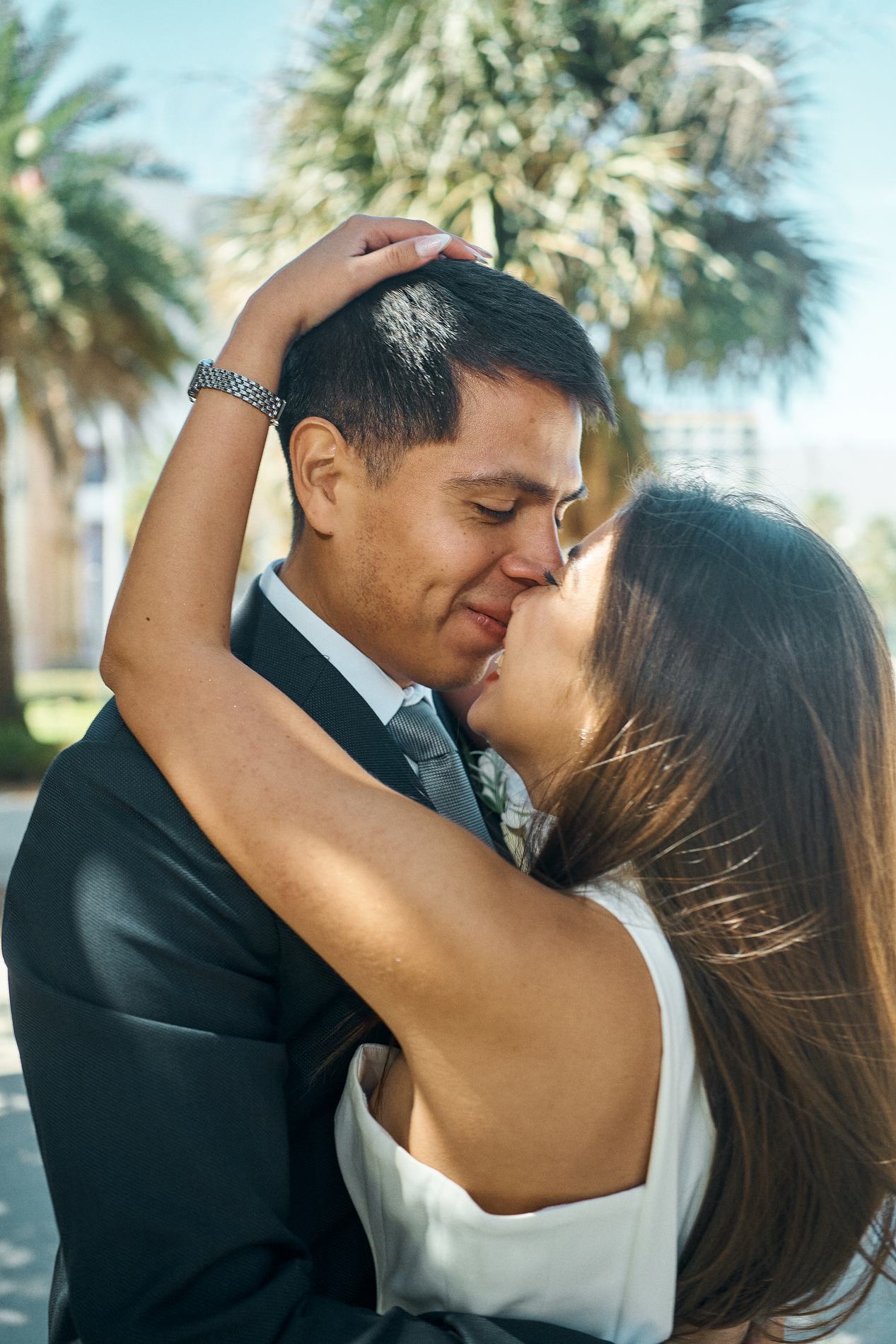 A bride and groom kissing under the palms in downtown Sarasota