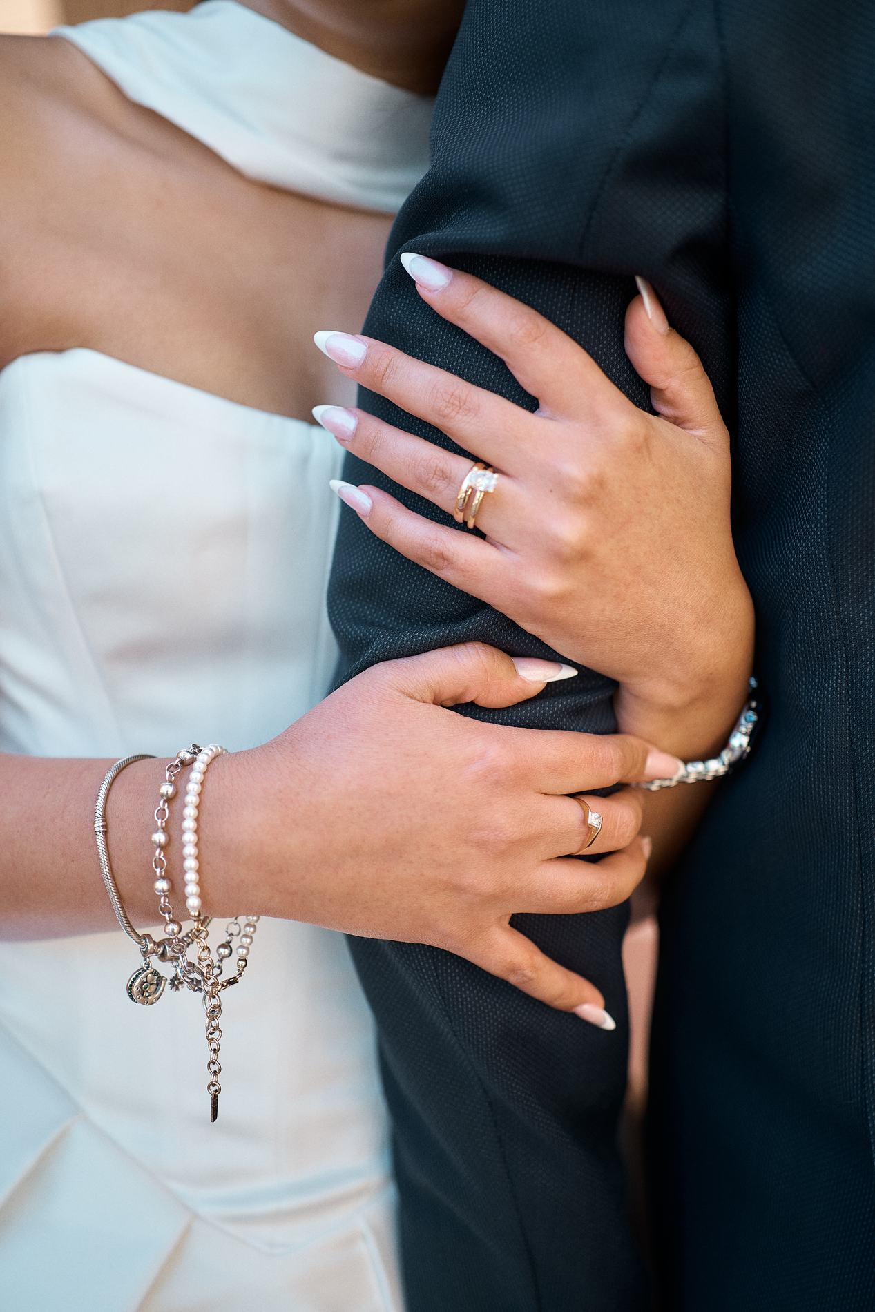 Her hand with the wedding ring on his arm, bracelets on her wrist