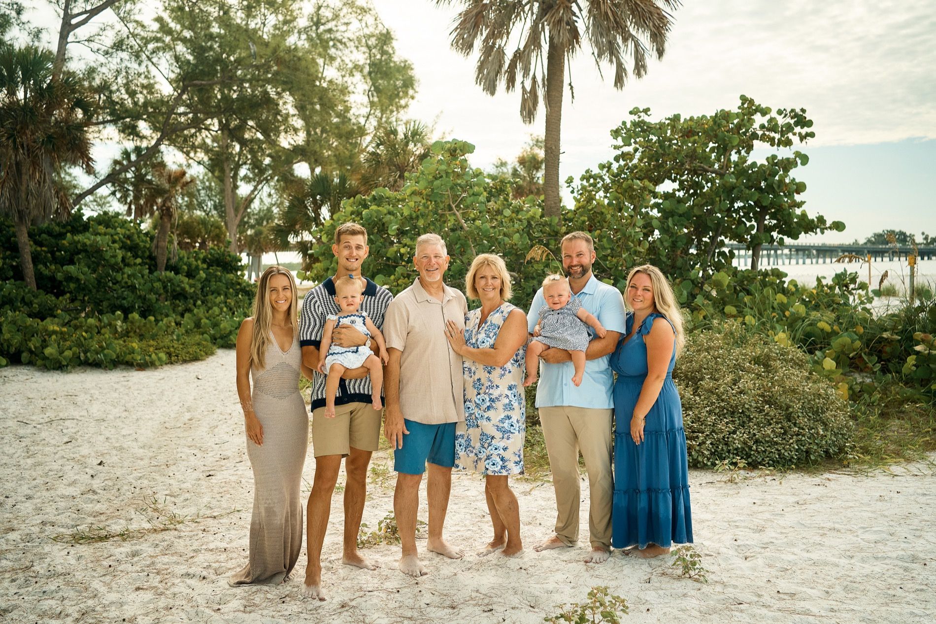 A large family standing together under the palms and sea grapes at Coquina Beach