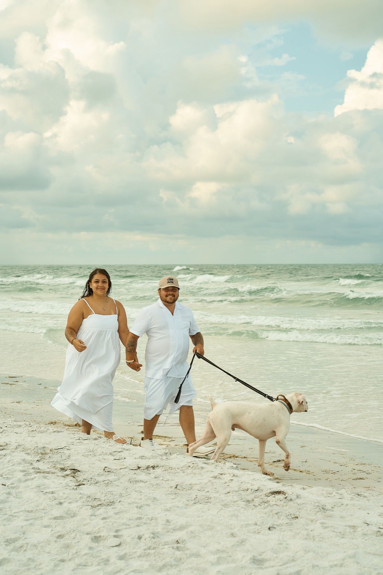 A couple walking along the water with their dog