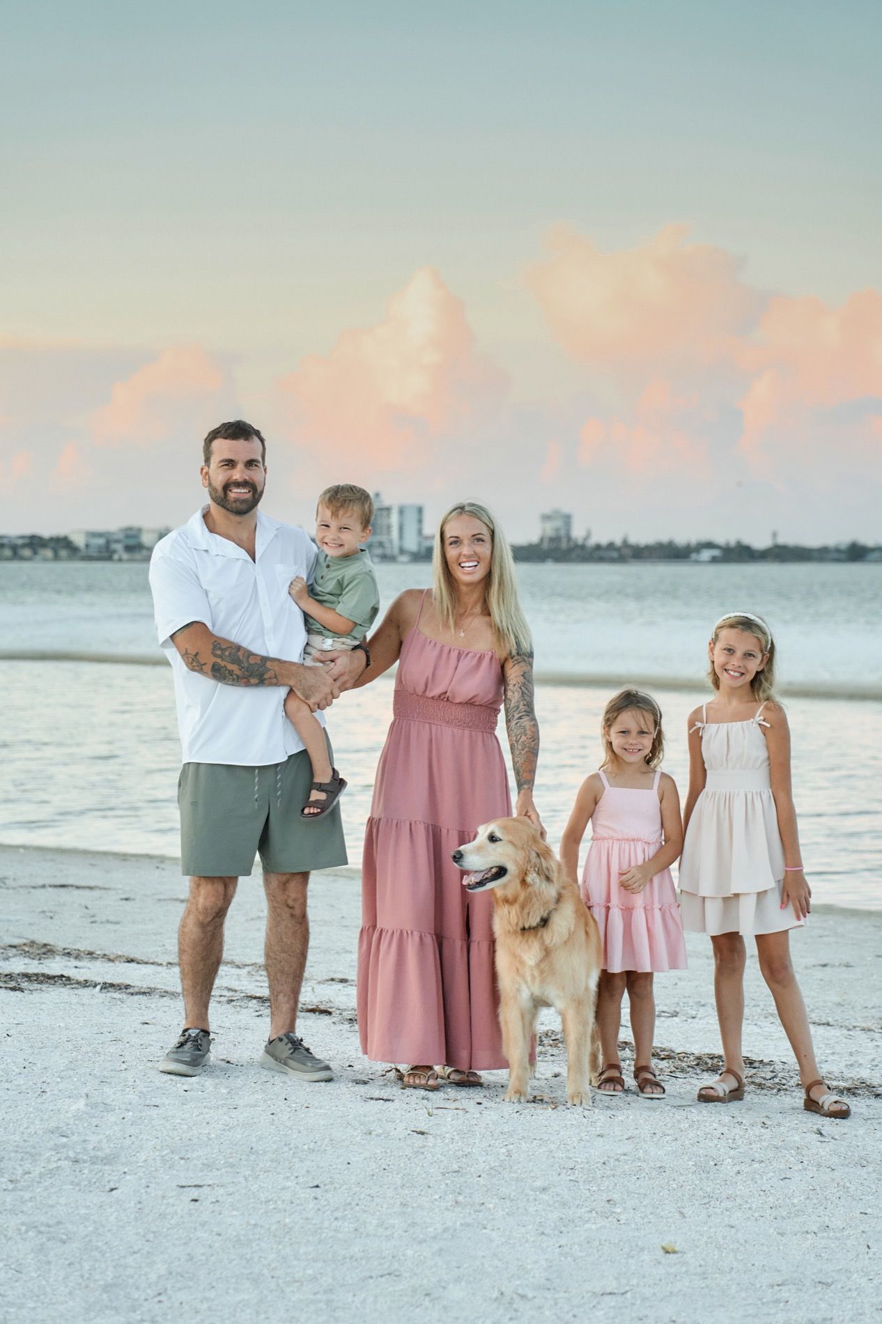 A family with two small children and their dog standing on the sand