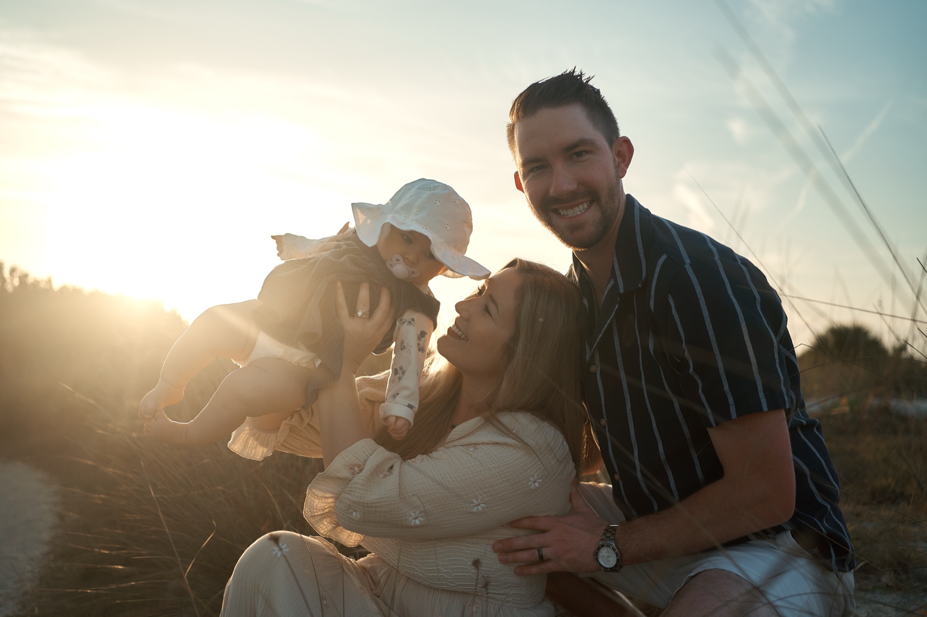 Parents lifting their baby in the golden evening light on a Sarasota beach