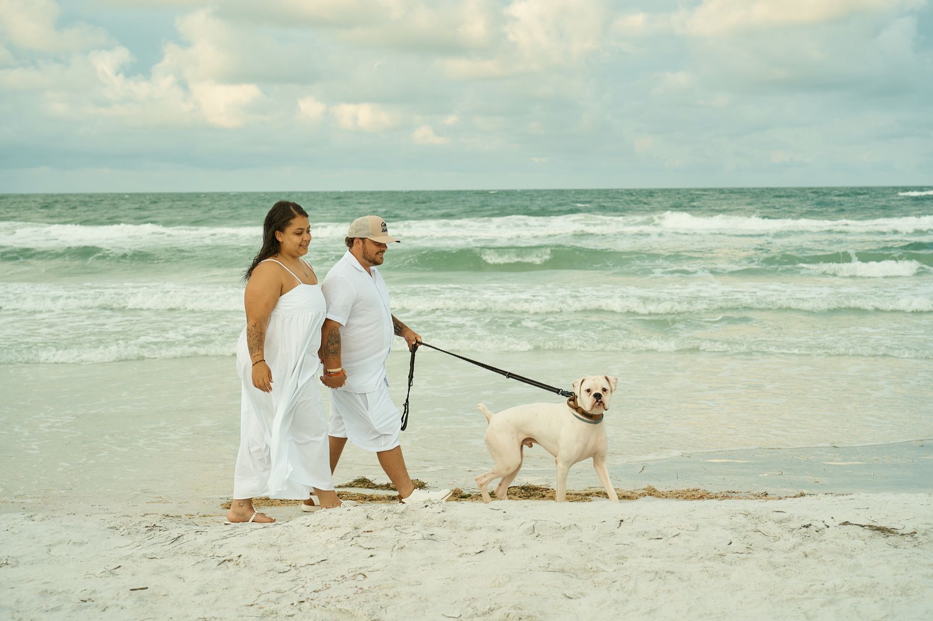 A family walking along the shoreline with their dog on a leash