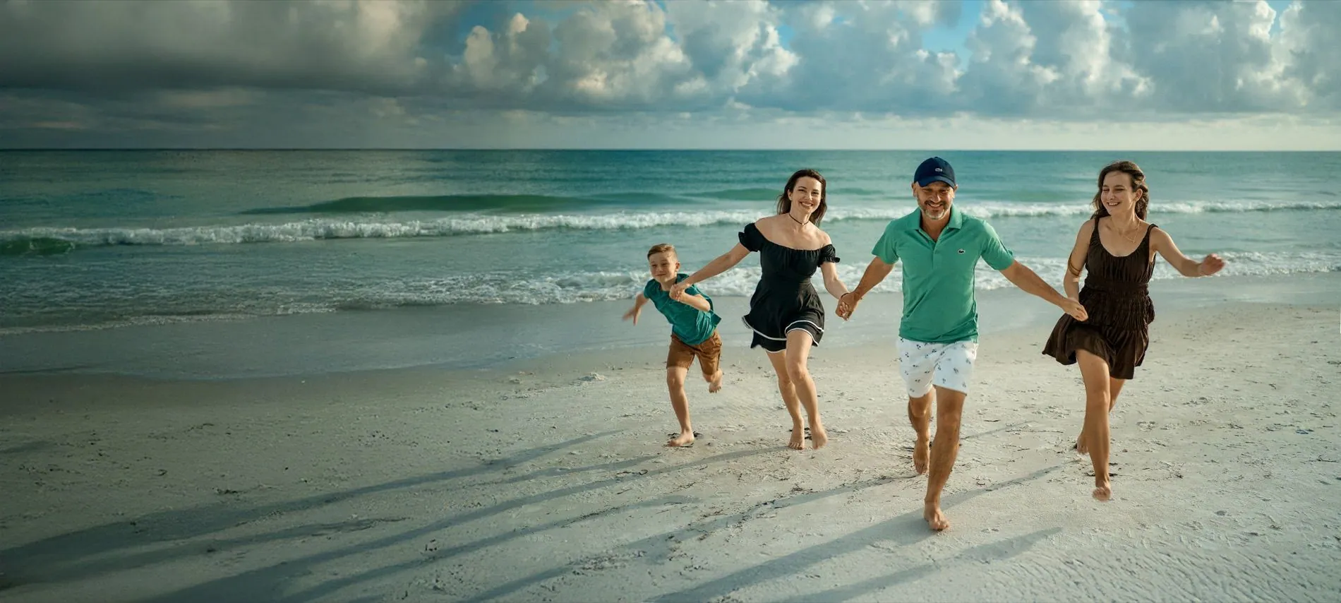A family of four running along the water on Siesta Key