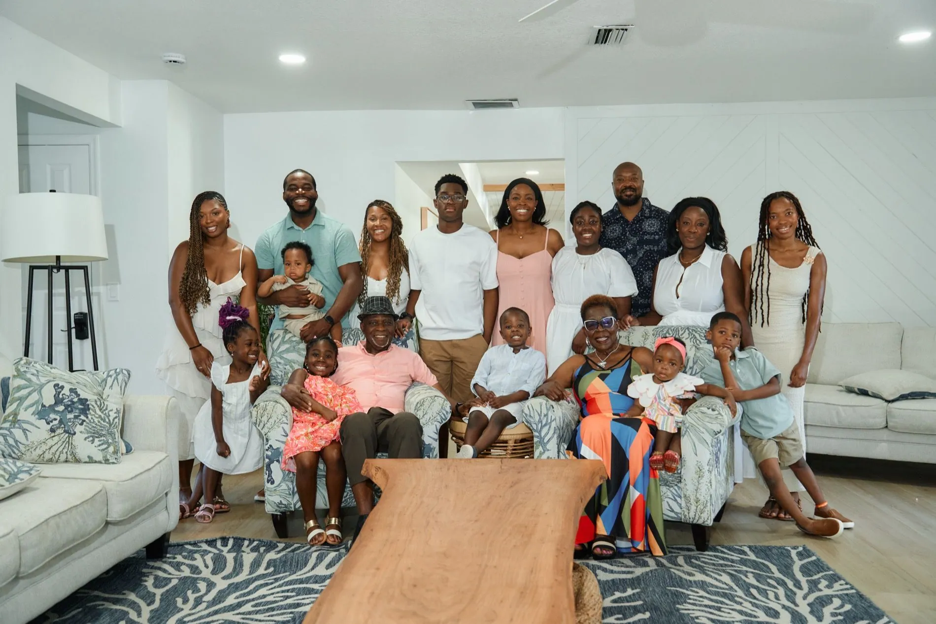 Three generations of one family, about seventeen people, gathered in a living room, the grandparents seated in the middle with grandchildren on their laps