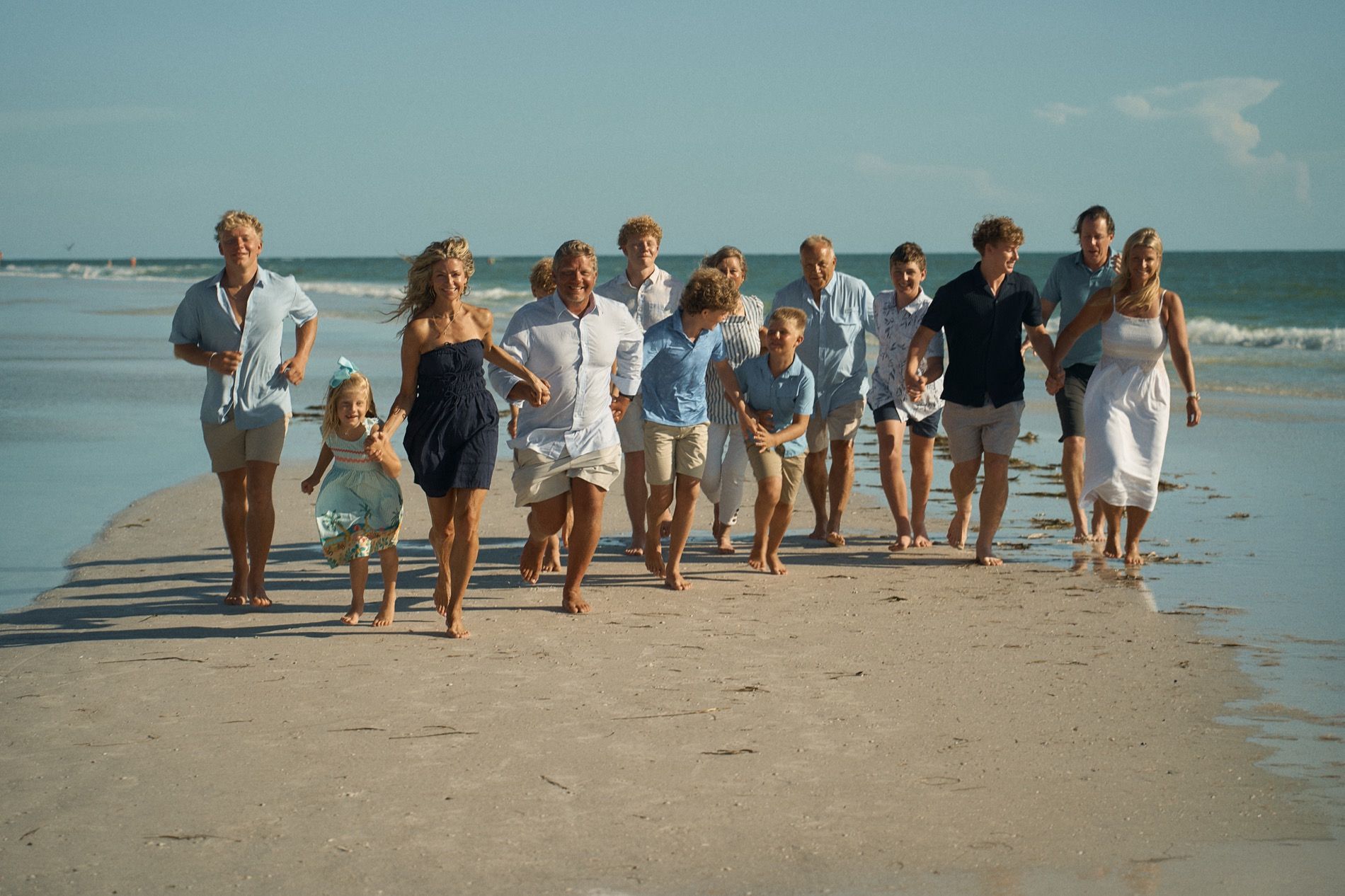 A large family running toward the camera along the water on a Sarasota beach