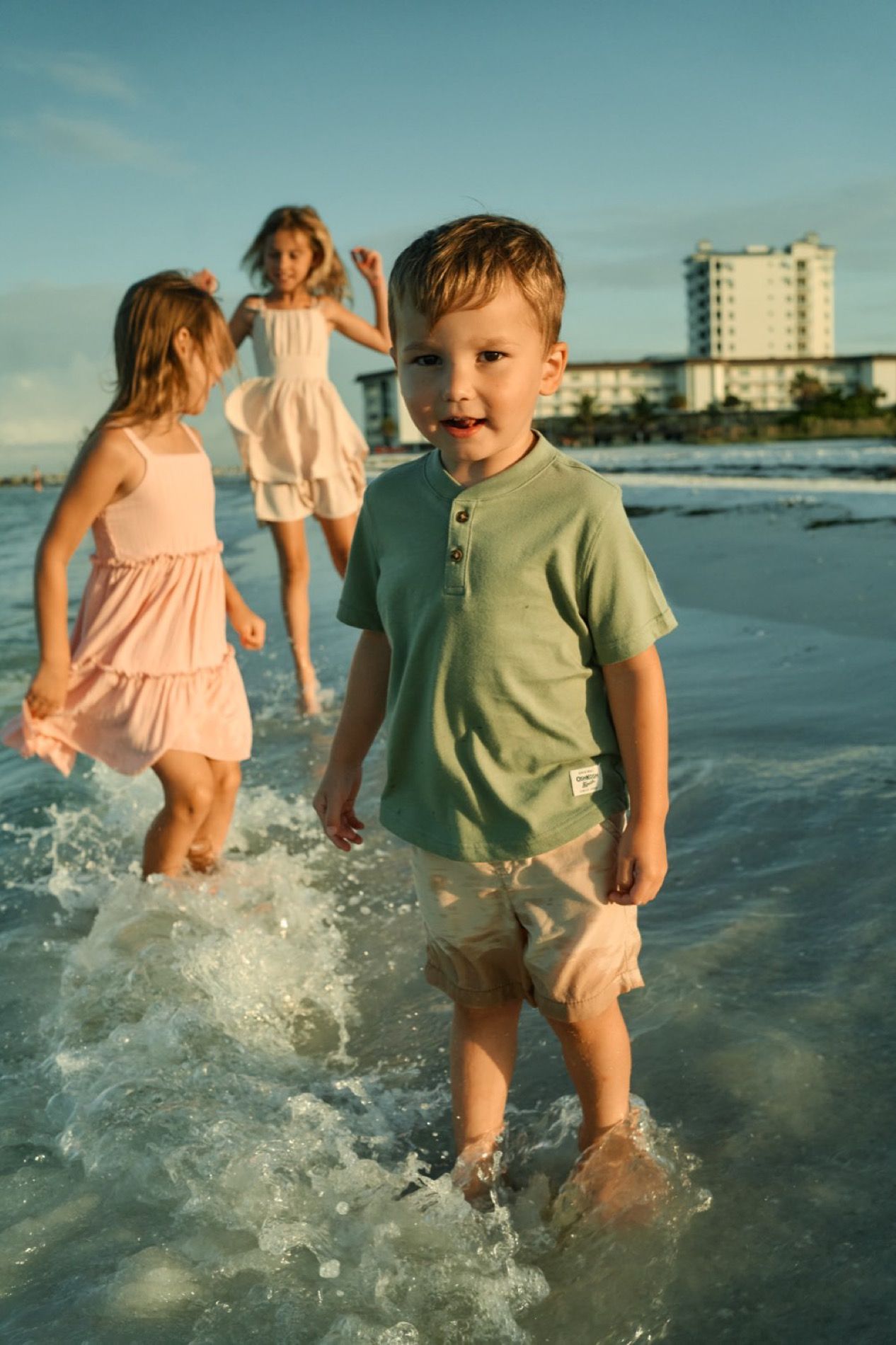 Three children playing in the shallow water in the evening light