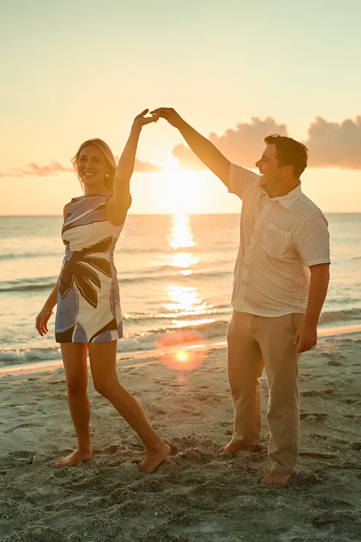 A couple dancing on the sand on Longboat Key just after he proposed, the sun setting between them