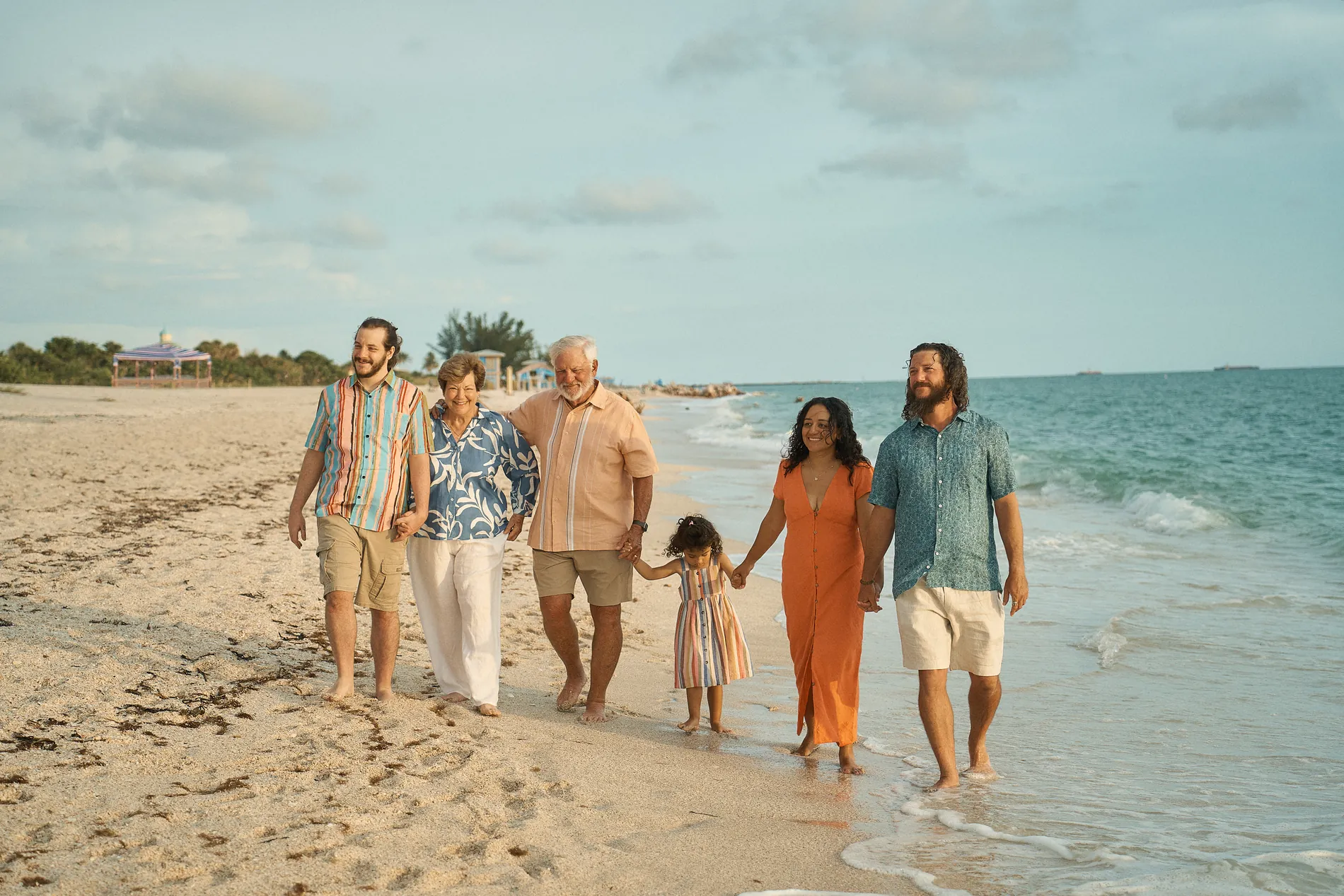 Three generations of one family walking along the edge of the water at Nokomis Beach