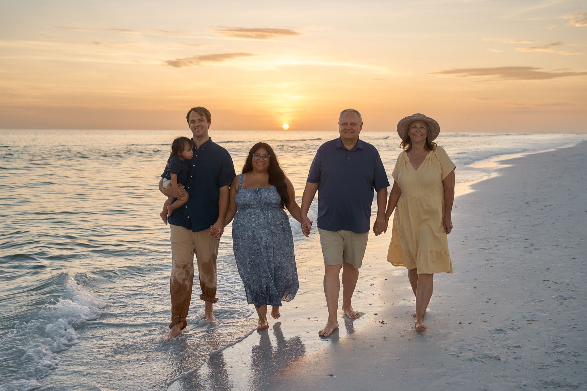 A family of four walking along the water on Siesta Key at sunset