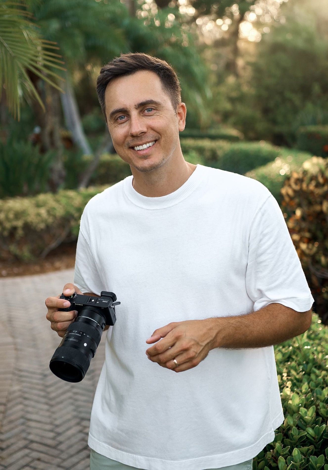 Yuriy holding his camera, palms and evening light behind him